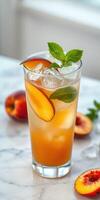 Refreshing summer drink with peach slices and mint leaves on a marble countertop photo