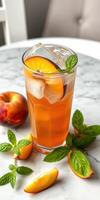 Refreshing iced beverage with peach slices and mint on a marble table photo