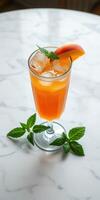 Refreshing peach iced beverage served in a tall glass with mint leaves on a marble table photo