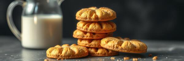 Freshly baked cookies stacked beside a glass of milk on a dark background photo