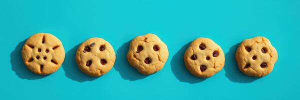 Freshly baked cookies with different designs lined up on a vibrant turquoise background photo