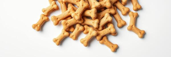 Crunchy dog treats shaped like bones piled on a white surface for pet enjoyment photo