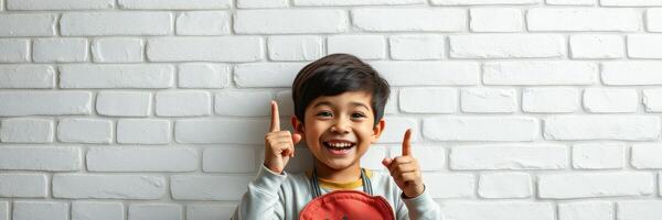 Happy child celebrating success with a big smile in front of a white brick wall photo