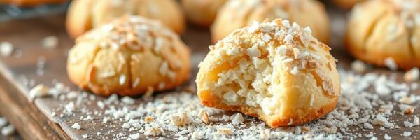 Delightful coconut cookies on a wooden tray showcasing bite marks and shredded coconut topping photo