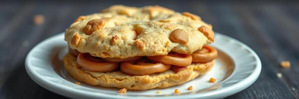 Delicious freshly baked cookie layered with golden caramel slices on a white plate photo