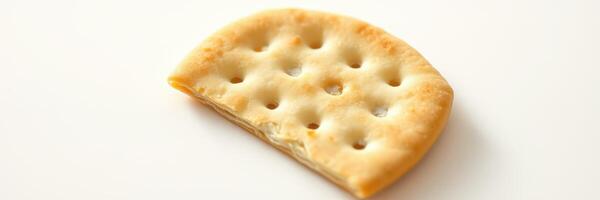 Cracker with holes rests on a plain background, showcasing its texture and shape in a simple still life photo