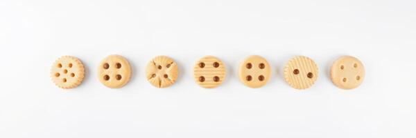 Unique wooden buttons arranged in a line on a white surface showcasing various designs and textures photo
