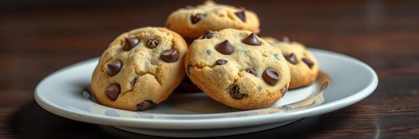 Freshly baked chocolate chip cookies on a white plate served on a wooden table photo