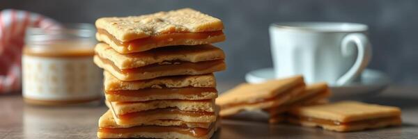 Delicious caramel-filled cookies stacked on a wooden table with a cup of tea in the background photo