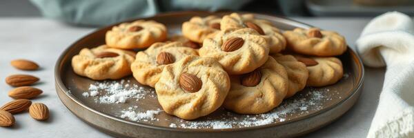 Freshly baked almond cookies arranged on a serving platter with scattered almonds and powdered sugar photo