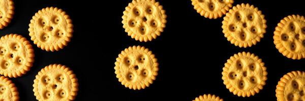Colorful round crackers arranged in a playful pattern on a black background during a bright day photo