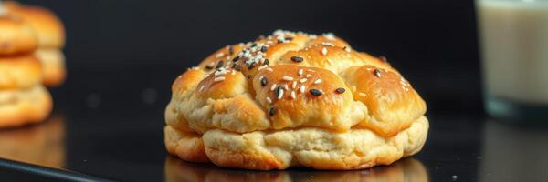 Freshly baked bread rolls with sesame seeds displayed on a dark countertop photo