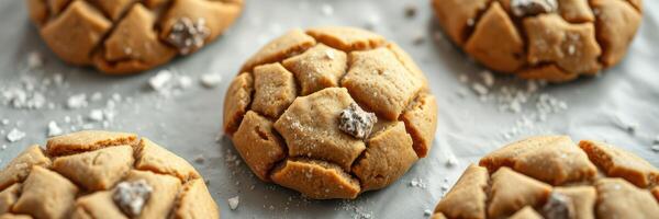 Deliciously cracked cookies sprinkled with sea salt on a parchment lined baking tray in a warm kitchen setting photo