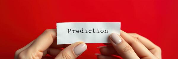 Hands holding a paper with the word 'Prediction' against a red background highlighting foresight and insight photo