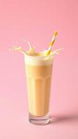 Refreshing beverage with creamy texture splashing in a tall glass against a pink background photo