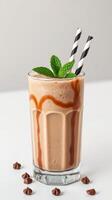 Chocolate milkshake with mint garnish and striped straws served in a clear glass photo