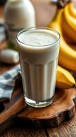 Creamy banana smoothie sits beside fresh bananas on a rustic wooden countertop with a cozy ambiance photo