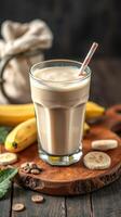 Delicious banana smoothie served in a glass with striped straw on a wooden cutting board surrounded by fresh bananas and coffee beans photo