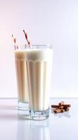 Creamy milkshakes with striped straws served on a light surface alongside chocolate sticks photo