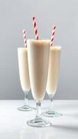 Delicious creamy milkshakes served in tall glasses with red and white striped straws garnishing a minimalistic backdrop photo