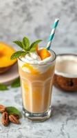 Refreshing mango smoothie topped with whipped cream and mint leaves served in a tall glass photo