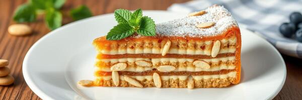 Delicious slice of layered dessert with nuts and mint on a plate with wooden background photo