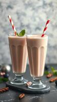 Refreshing chocolate milkshakes with striped straws and mint garnish served on a dark table photo