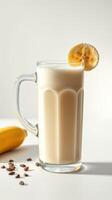 Refreshing banana smoothie served in a tall glass with a slice of banana on the rim and scattered coffee beans on the table photo