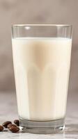 Fresh milk in a clear glass is beautifully displayed with coffee beans on a marble surface photo