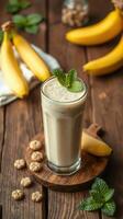 Creamy banana smoothie served with fresh mint and cookies on a rustic wooden table photo