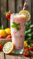 Refreshing strawberry lemonade drink served in a tall glass with fresh fruits on a wooden table photo