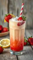 Refreshing strawberry drink served in a tall glass garnished with fresh fruit and a striped straw photo