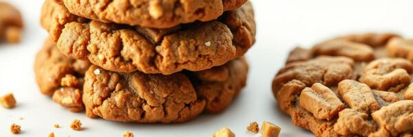 Freshly baked peanut butter cookies stacked on a white surface with crumbs scattered around photo