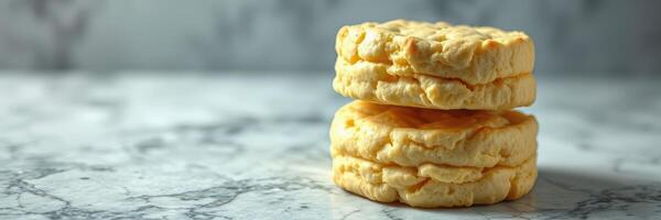 Fluffy homemade biscuits stacked on a marble countertop, showcasing their golden texture and inviting appearance for breakfast photo