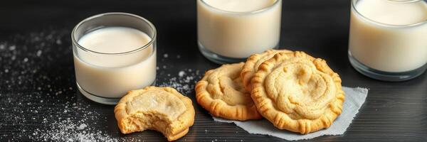 Freshly baked cookies served with cold milk in stylish glasses on a dark wooden surface photo