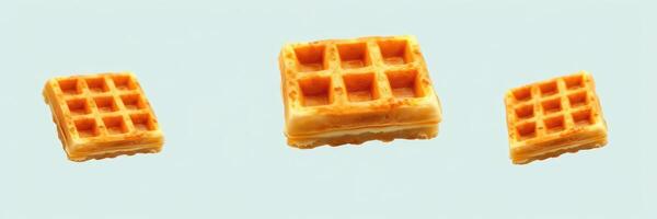 Waffles of various sizes arranged on light blue background showcasing texture and color contrasts photo