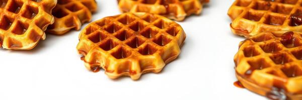 Waffles placed on a white surface with syrup drizzled on top during a breakfast setting photo