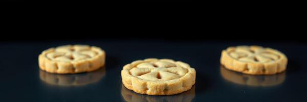 Three round cookies with intricate designs displayed on a reflective surface against a dark background photo