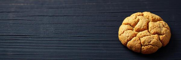 Freshly baked cookie resting on a dark wooden surface with a rustic finish in soft lighting photo
