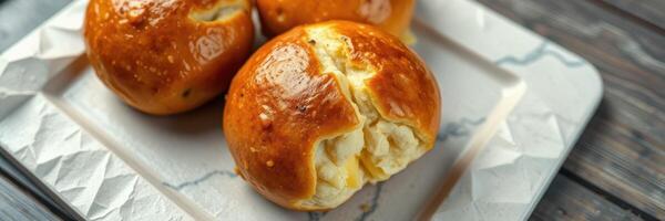Freshly baked golden bread rolls stuffed with creamy filling on a plain plate photo