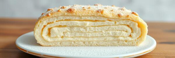 Soft cream roll dessert on a plate showcasing layers of fluffy texture and sweet filling during a bright kitchen setting photo