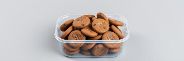 Freshly baked chocolate chip cookies displayed in a clear container on a neutral surface photo