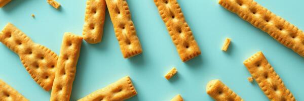 Crispy golden crackers scattered on a turquoise background showcasing their crunchy texture and playful arrangement photo