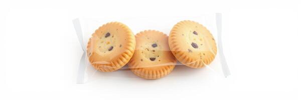 Three round chocolate chip cookies wrapped in clear plastic for freshness on a white background photo