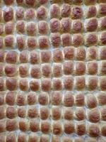 closeup of Rows of bread-like or bun-like objects arranged neatly .Pav . They appear golden-brown, likely freshly baked.Pav is a soft, slightly sweet, square-shaped bread roll photo