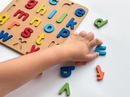 Child learning alphabet with colorful puzzle blocks on white background photo