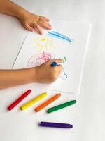 Childs colorful drawing of sun and clouds with crayons on white paper photo