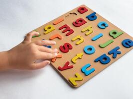 Child learning with colorful alphabet puzzle on white background photo