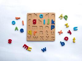 Colorful alphabet puzzle with wooden board and loose letters on white background photo