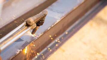 Skilled metalworker uses torch to cut through steel. Sparks fly as craftsman demonstrates precision in industrial workshop. Concept of balancing risk and expertise in dangerous metalworking processes. photo